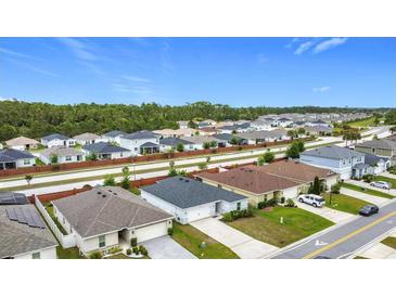 Wide aerial view of a suburban neighborhood with well-maintained homes and green spaces on a bright day at 16369 Yelloweyed Dr, Clermont, FL 34714