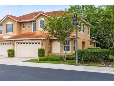 Two-story townhome showing the front entrance, a two car garage, and well manicured shrubbery at 1998 Michael Tiago Cir, Maitland, FL 32751