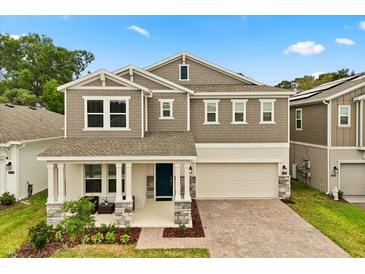 Charming two-story home with a cozy front porch and well-manicured lawn and a brick paver driveway at 4216 Jespersen St, Apopka, FL 32712