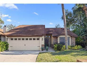 Charming single-story home with a two-car garage, manicured lawn, and mature landscaping at 7027 Villa Estelle Drive, Orlando, FL 32819
