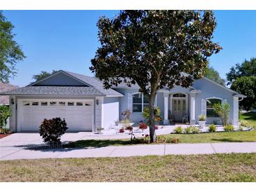Charming single-story home with beautifully landscaped front yard, a well-maintained lawn and flowering trees at 827 Princeton Dr, Clermont, FL 34711