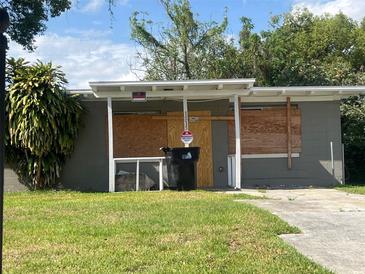 A single-story home with a covered front entrance, gray cinderblock exterior and a lawn at 1515 20Th St, Orlando, FL 32805
