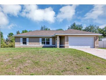 Charming single-story home showcasing a two-car garage, well-kept lawn, and traditional architecture at 1883 Sw 160Th Pl, Ocala, FL 34473