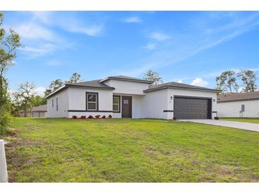 Charming single-story home featuring a well-manicured lawn, a gray garage door and black trim at 236 Marion Oaks Mnr, Ocala, FL 34473