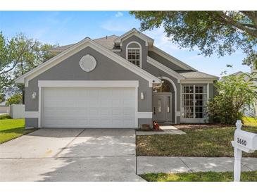 Charming gray home featuring a two-car garage, arched entry, and well-maintained lawn at 3660 Ventura Club Cir, Orlando, FL 32822