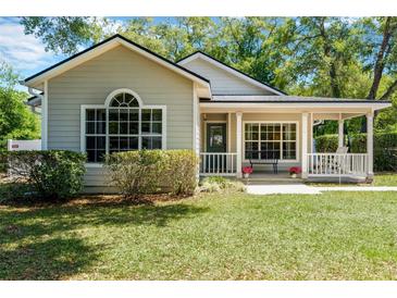 Charming single-story home featuring a landscaped yard, covered porch with seating, and updated windows at 441 S Blue Lake Ave, Deland, FL 32724