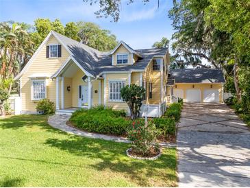 Charming yellow two-story home with a well-manicured lawn and a three car garage at 910 Cypress Ave, St Cloud, FL 34769