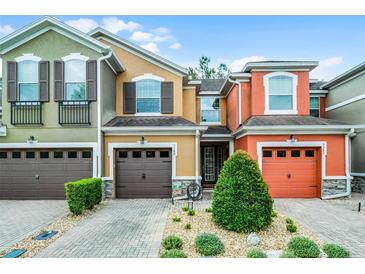 Colorful townhouses with garage, manicured shrubs and bushes, and paved driveway on a bright sunny day at 9349 Sweet Maple Ave, Orlando, FL 32832