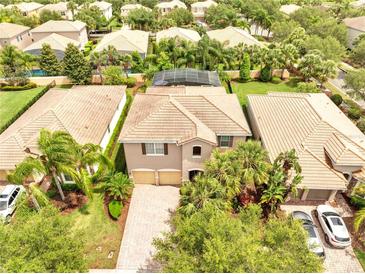Aerial view of a well-manicured, two-story home with tile roof and lush tropical landscaping at 11885 Padua Ln, Orlando, FL 32827