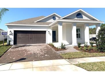 Charming single-story home with a brick driveway, two-car garage, and covered front porch with white pillars at 1374 Brentwood Dr, Kissimmee, FL 34746
