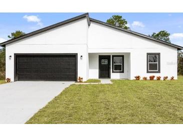 New construction home features a black garage door and a well manicured lawn at 14961 Sw 38Th Cir, Ocala, FL 34473