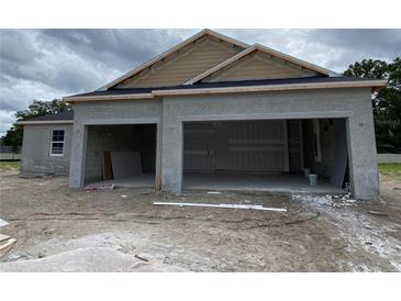 Unfinished stucco home with a three-car garage and architectural detailing under cloudy skies at 2644 Ravencliffe Ter, Oviedo, FL 32765
