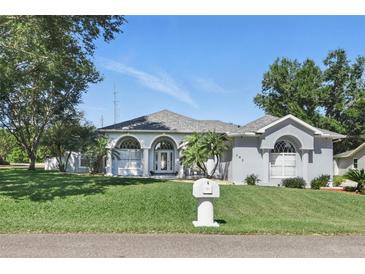 Elegant single-story home with arched entryway, well-manicured lawn, and lush landscaping at 392 Bayberry Dr, Polk City, FL 33868