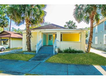 Charming yellow bungalow with a quaint porch, blue door, and mature palm trees at 611 Sanford Ave, Sanford, FL 32771
