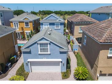 Lovely light blue home featuring a white garage door, well-manicured landscaping, and a paved driveway at 7409 Excitement Dr, Reunion, FL 34747