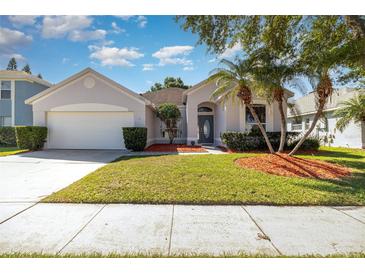 Charming single-story home featuring a well-manicured lawn, palm trees, and a two-car garage at 12213 Bohannon Blvd, Orlando, FL 32824