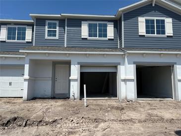 New two-story townhome showing a blue facade, white trim, open garage, and a door at 14910 Harvest St, Orlando, FL 32824