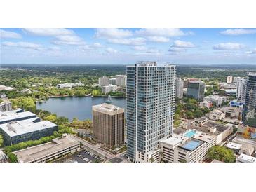 Stunning aerial view of the condo building overlooking a lake with a sailboat and lush green landscape at 150 E Robinson St # 1219, Orlando, FL 32801