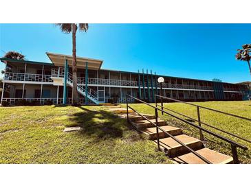 Two-story condo building with staircase and walkway, complemented by well-maintained landscaping on a sunny day at 1600 W Lake Parker Dr # C24, Lakeland, FL 33805