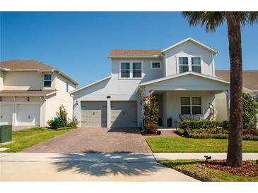 Charming two-story home with a two-car garage, brick driveway, manicured lawn, and covered front porch at 18907 Rawson St, Orlando, FL 32827