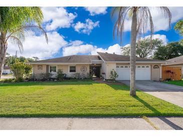 Charming single-story home with a well-manicured lawn, mature palm trees, and a two-car garage at 201 Twelve League Cir, Casselberry, FL 32707