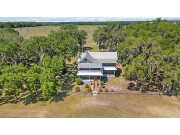 Inviting two-story home featuring a metal roof, charming front porch, and mature trees with Spanish moss at 3650 Lake Tohopekaliga Rd, St Cloud, FL 34772