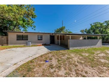 Single story home featuring a concrete driveway, covered carport, and neutral colored exterior in a sunny setting at 5201 Palisades Dr, Orlando, FL 32808