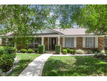 Charming brick home with manicured lawn, walkway, and mature landscaping; features a welcoming entryway at 105 Valley Ct, Longwood, FL 32779