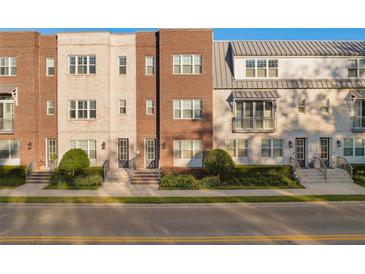 Charming townhome exterior featuring red brick, manicured landscaping, and inviting entryways under a clear sky at 129 S Park Ave # 129, Winter Garden, FL 34787