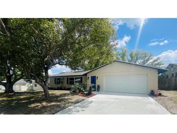 Charming single-story home with a well-manicured lawn, mature shade tree, and a blue front door at 1414 Meadowlark St, Longwood, FL 32750