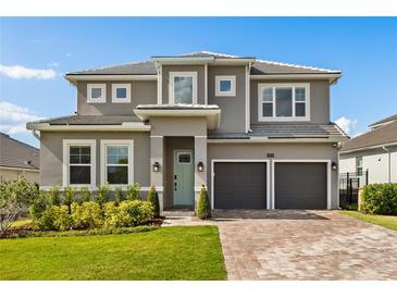 Two-story home featuring a two-car garage, brick driveway, well-manicured lawn and light-green front door at 16018 Volterra Pt, Bella Collina, FL 34756