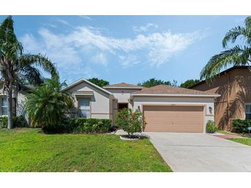 Charming single-story home featuring a well-manicured lawn, lush landscaping, and a welcoming facade at 16810 Sunrise Vista Dr, Clermont, FL 34714