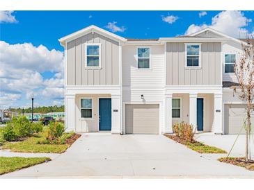 Charming townhome exterior with a blue front door, neutral paint and a one car garage with landscaping at 2413 Brook Marsh Loop, Kissimmee, FL 34747