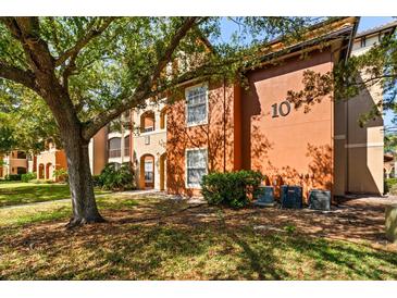 Exterior view of an apartment building with an orange facade and landscaped yard at 5524 Metrowest Blvd # 210, Orlando, FL 32811