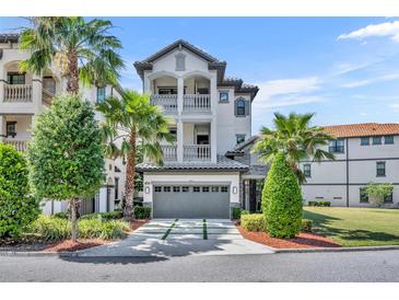Elegant three-story home featuring a gray garage door, two balconies, and lush tropical landscaping at 7613 Toscana Blvd, Orlando, FL 32819