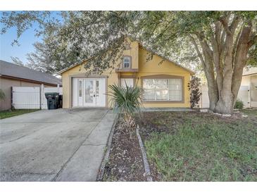 Charming single-story home with yellow siding, mature trees, and a spacious driveway and front entry at 9447 Dearmont Ave, Orlando, FL 32825