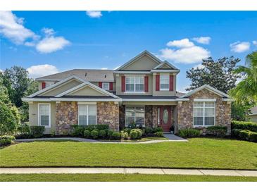 Charming two-story home featuring stone accents, red shutters, and a beautifully landscaped front yard at 1065 Cavan Dr, Apopka, FL 32703