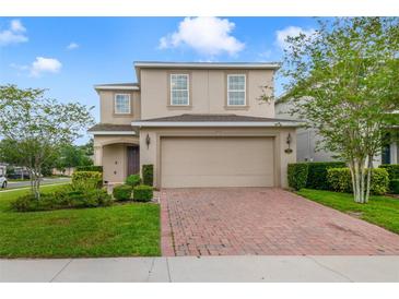 Two-story home featuring a well-maintained lawn, a brick-paved driveway, and an attached two-car garage at 1354 Riley Cir, Deland, FL 32724