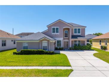 Two-story home showcasing neutral stucco, well-manicured lawn and mature shrubbery at 2340 Hinsdale Dr, Kissimmee, FL 34741
