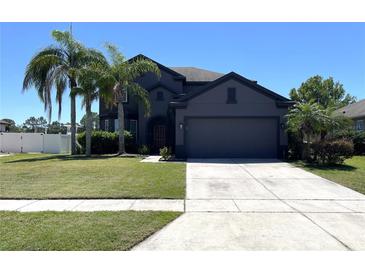 Beautiful two-story home with a well-manicured lawn and mature palm trees providing shade at 2865 Running Brook Cir, Kissimmee, FL 34744