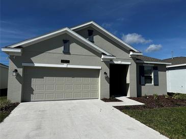 Charming single-story home featuring a two-car garage, well-manicured lawn, and neutral exterior paint at 34071 Sky Blossom Cir, Leesburg, FL 34788