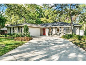 Charming home with a well-manicured lawn, a red door, and an attached two-car garage at 3517 Merivale Dr, Casselberry, FL 32707