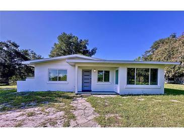 Charming single-story home featuring a modern front door, clean white stucco, and large windows at 407 Sheryl Dr, Deltona, FL 32738