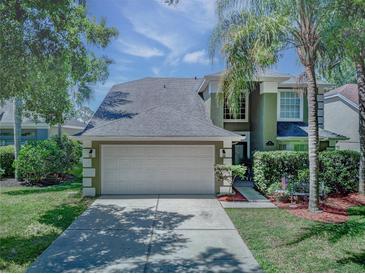 Charming two-story home featuring an attached garage, lush landscaping, and a welcoming entryway at 821 N Lake Claire Cir, Oviedo, FL 32765
