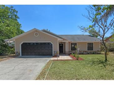 Charming single-story home with a well-manicured lawn, stone accents, and a two-car garage at 10030 Cheshunt Dr, Orlando, FL 32817