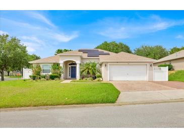 Charming single-story home with a well-manicured lawn, mature landscaping, and a welcoming entryway at 114 Dolcetto Dr, Davenport, FL 33897