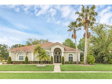 Charming single-story home featuring a tile roof, manicured lawn, and mature palm trees at 1518 Shadowmoss Cir, Lake Mary, FL 32746