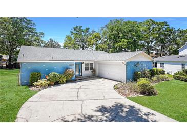 Charming single-story home featuring a blue brick exterior, well-maintained landscaping, and a paved driveway leading to the garage at 222 Paul Mcclure Ct, Casselberry, FL 32707