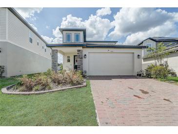 Charming two-story home with manicured lawn, brick driveway, and stone pillar accents at 2412 Gold Dust Dr, Clermont, FL 34715