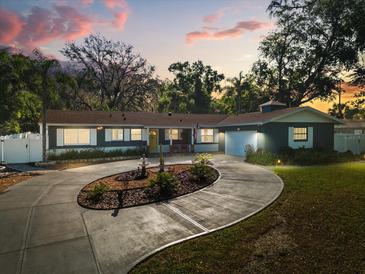 Charming single story home with an inviting circular driveway and lush landscaping at dusk at 2945 Southgate Ter, Orlando, FL 32818